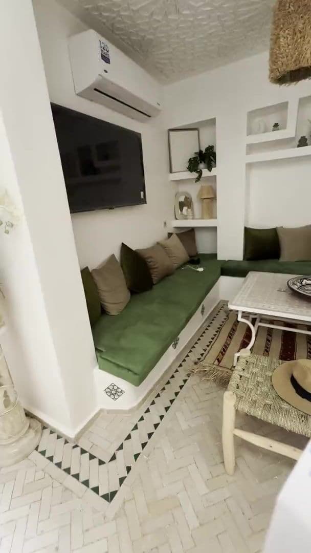 Salon aux banquettes vertes avec table basse en zellige